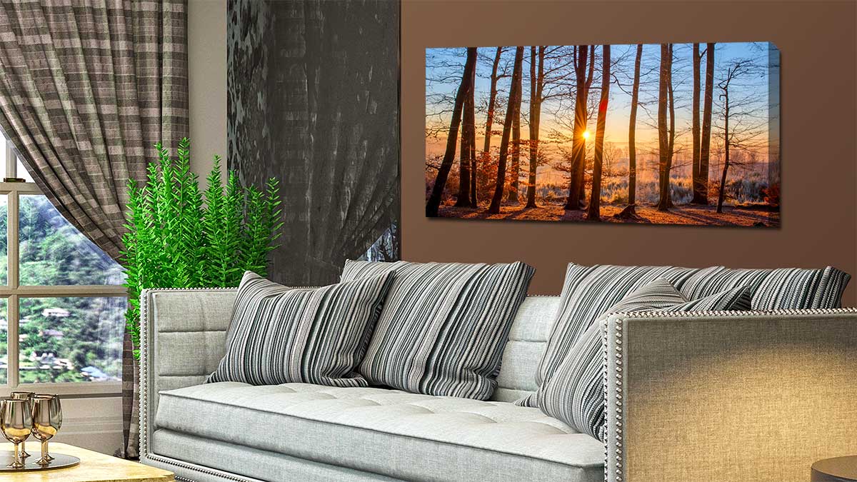 Stylish sitting room with a canvas print depicting a misty sunset in a wintry woodland.