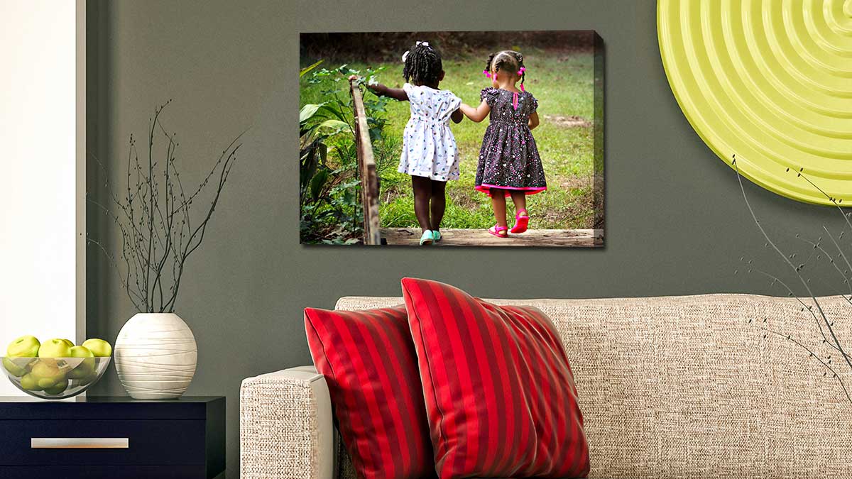 Canvas print of two little girls holding hands as they walk across a garden bridge