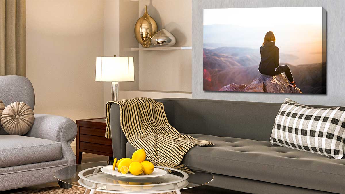 Canvas print depicting a woman sitting at the top of a mountain hung in a modern sitting room