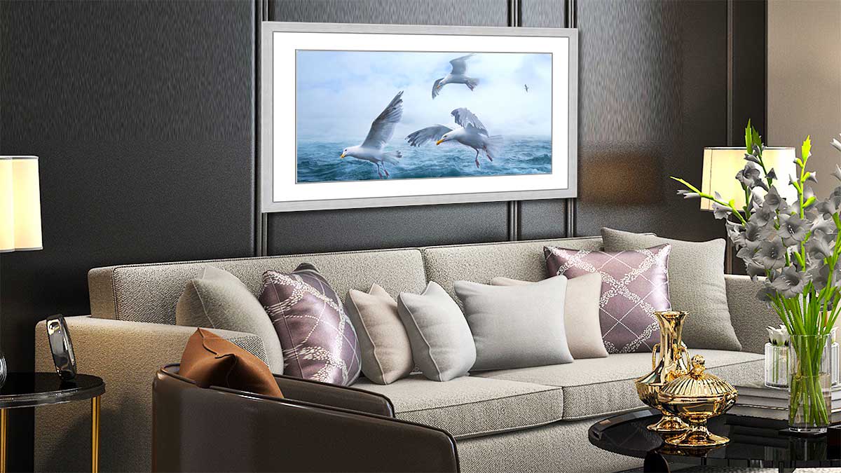 Framed poster featuring a seascape with gulls hung over an elegant settee