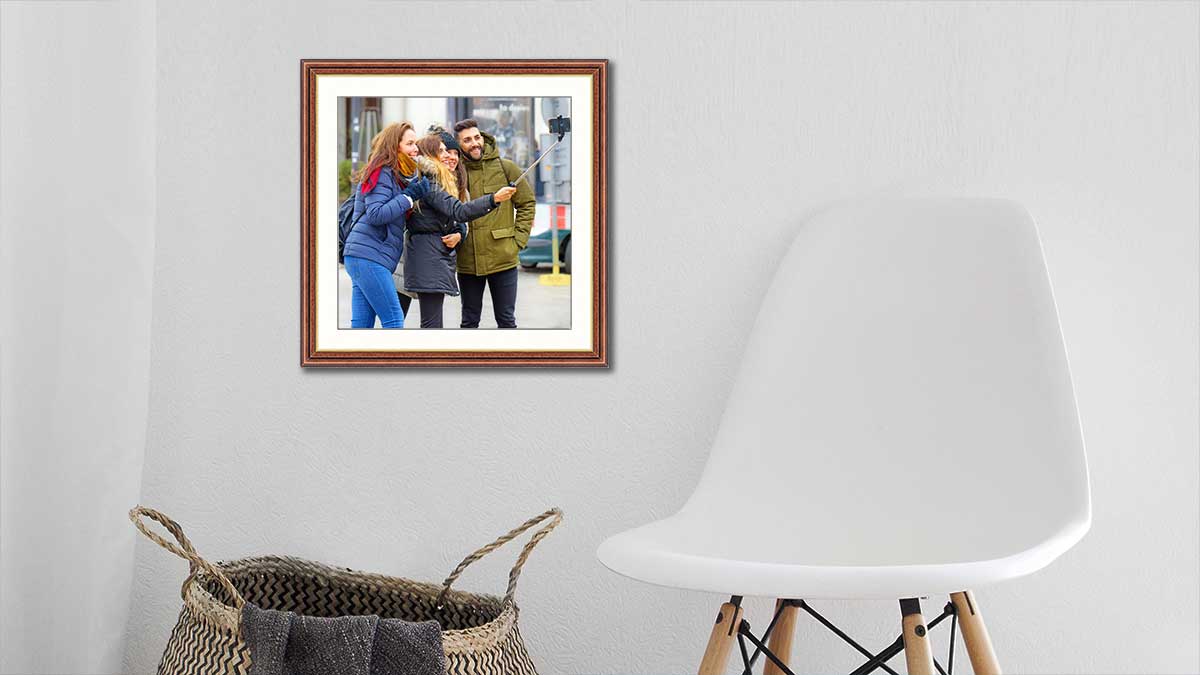 A picture of a group of friends captured whilst taking a selfie, framed in a walnut frame with a gold sight edge.