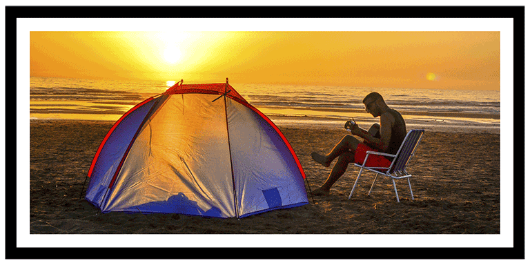 Framed poster showing a picture of a man camping on a beach in the sunset