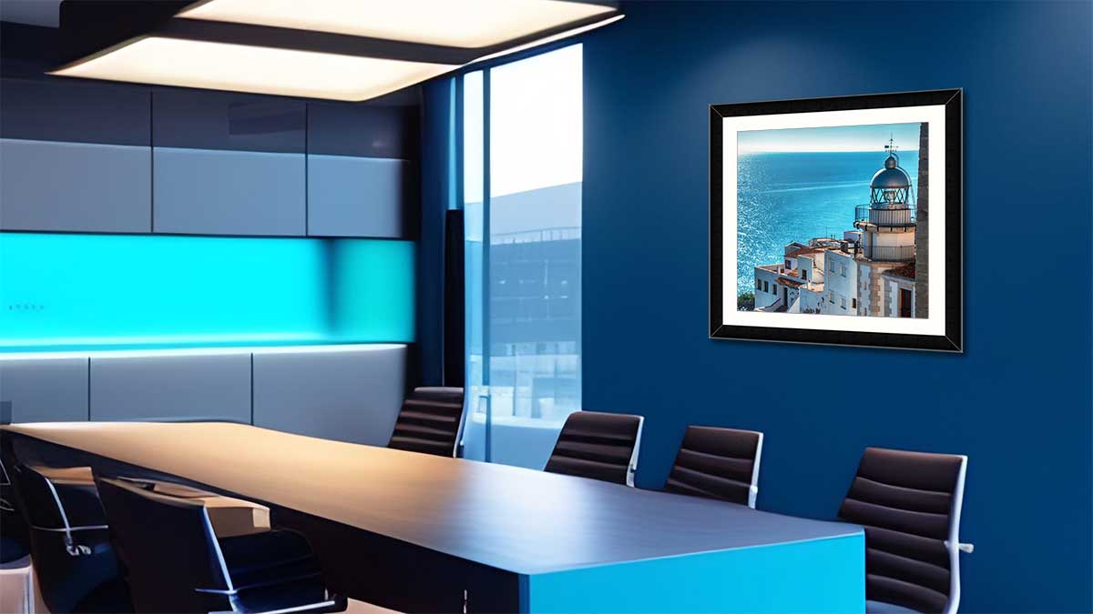 Photo of greek island with the blue sea behind, framed in a simple black frame in an office meeting room with black chairs and blue walls