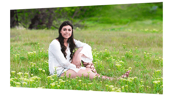 Photo print showing a beautiful meadow with a young woman sitting among the wildflower